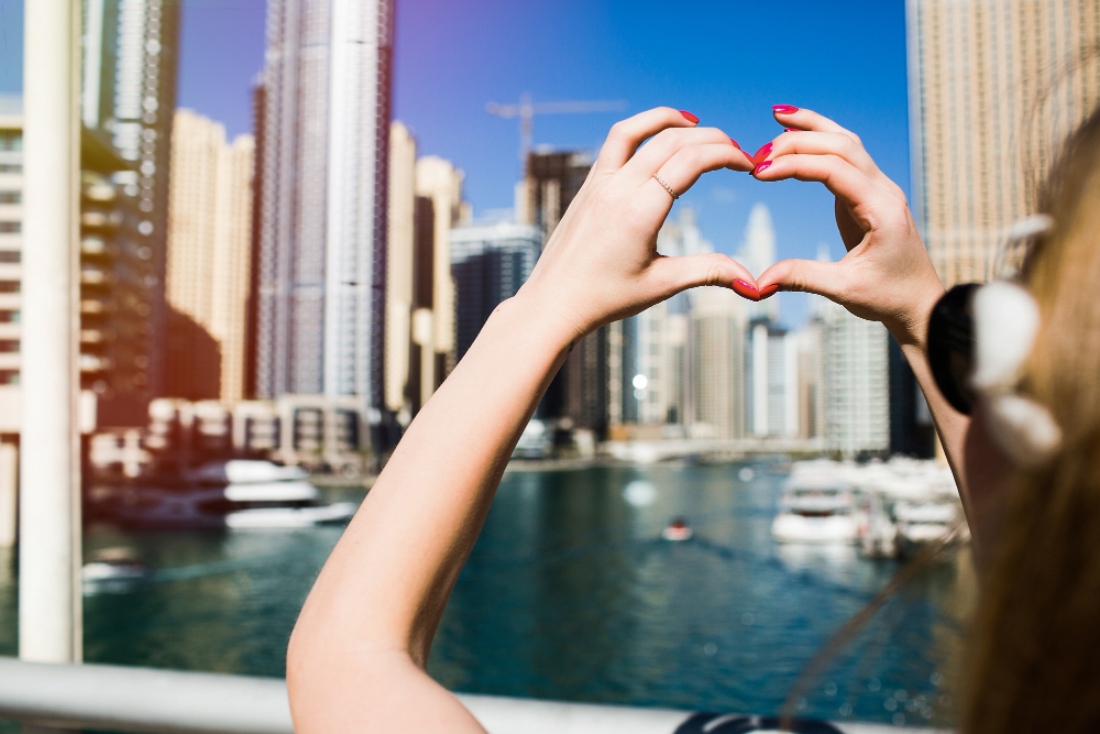 Dating in Dubai as an expat: person making a heart shape with their hands overlooking Dubai Marina